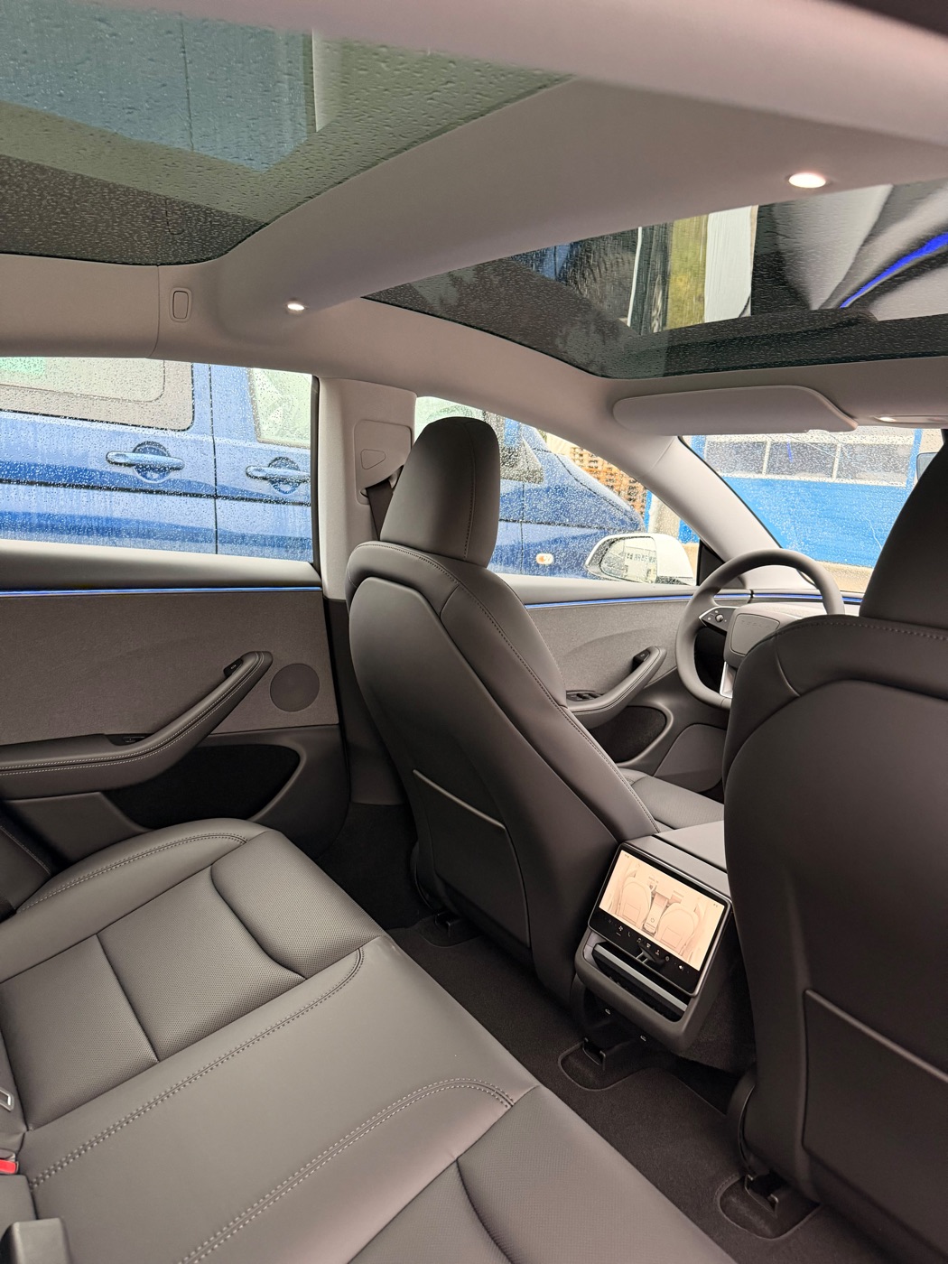 Innenraum des Tesla Model 3 mit dunklen Sitzen und Panorama-Glasdach