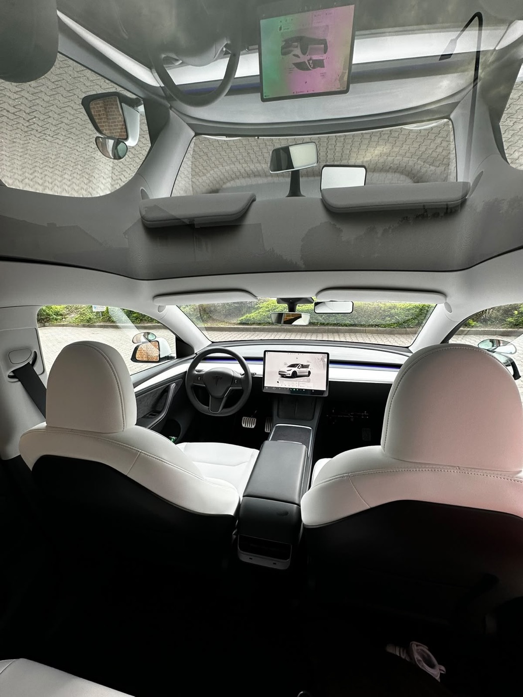 Heller Innenraum des Tesla Model Y mit weißen Sitzen und Panorama-Glasdach