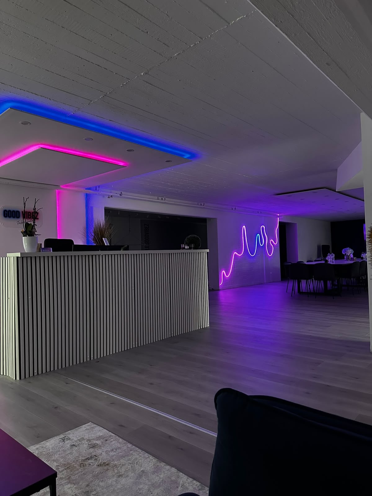 Empfangsbereich der Fahrschule Good Vibez mit pinker und blauer Neonbeleuchtung