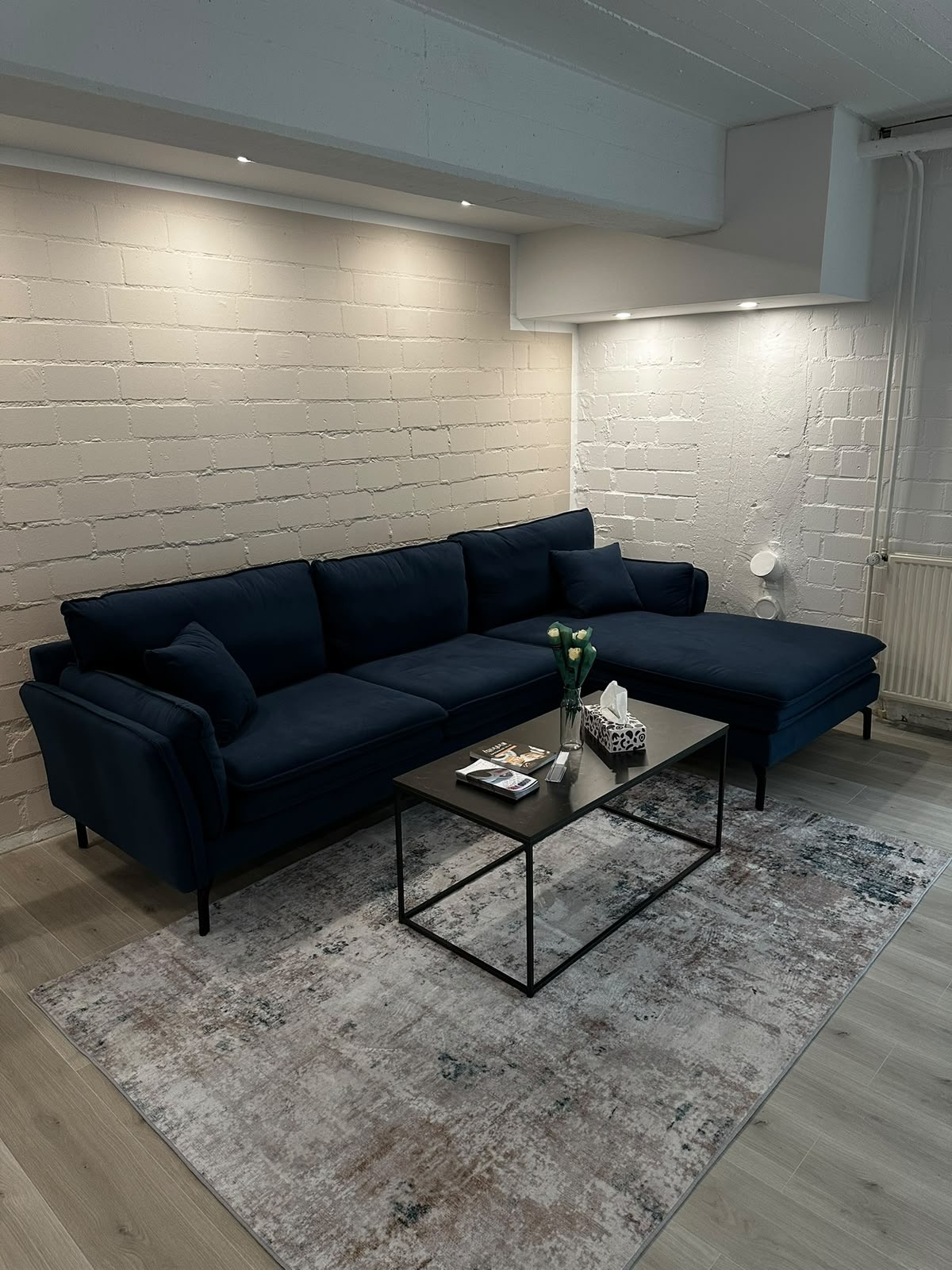 Lounge mit dunkelblauem Sofa und Couchtisch in der Fahrschule Good Vibez